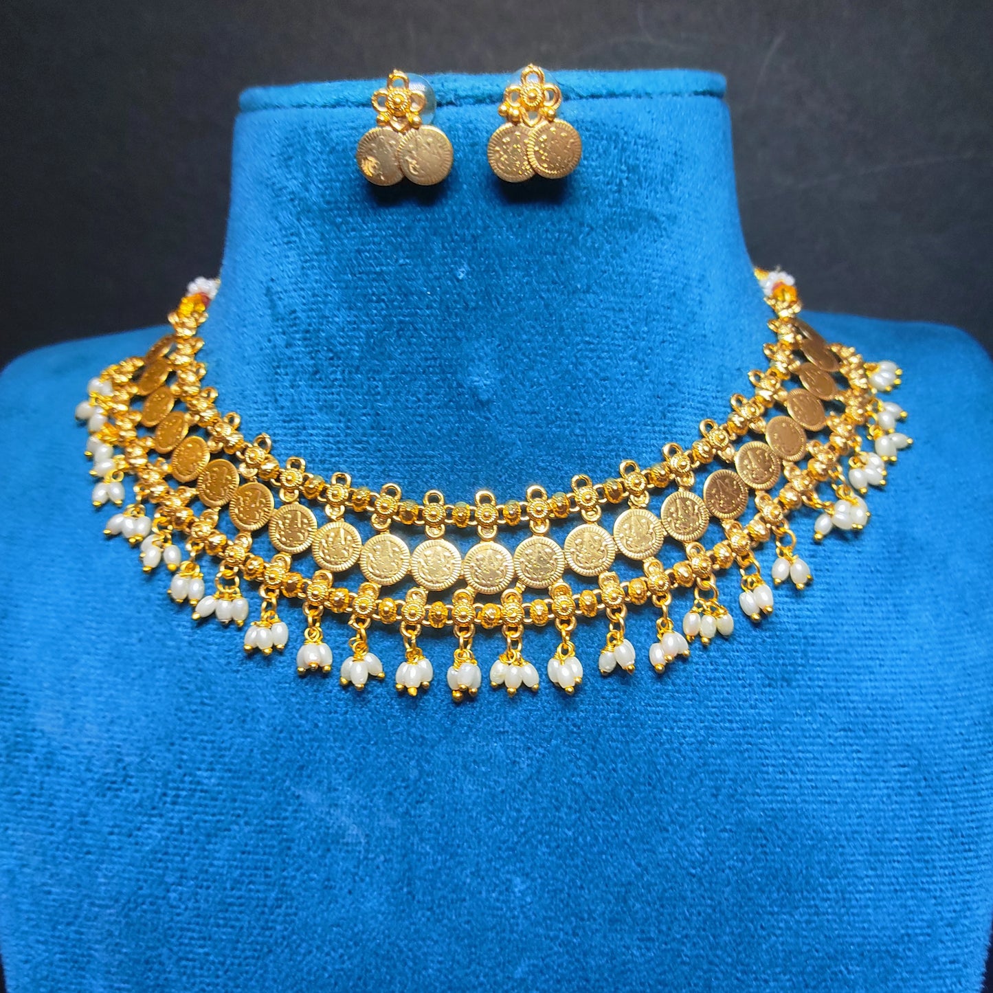Antique Gold Finish necklace and earrings on a blue mannequin bust against a dark background