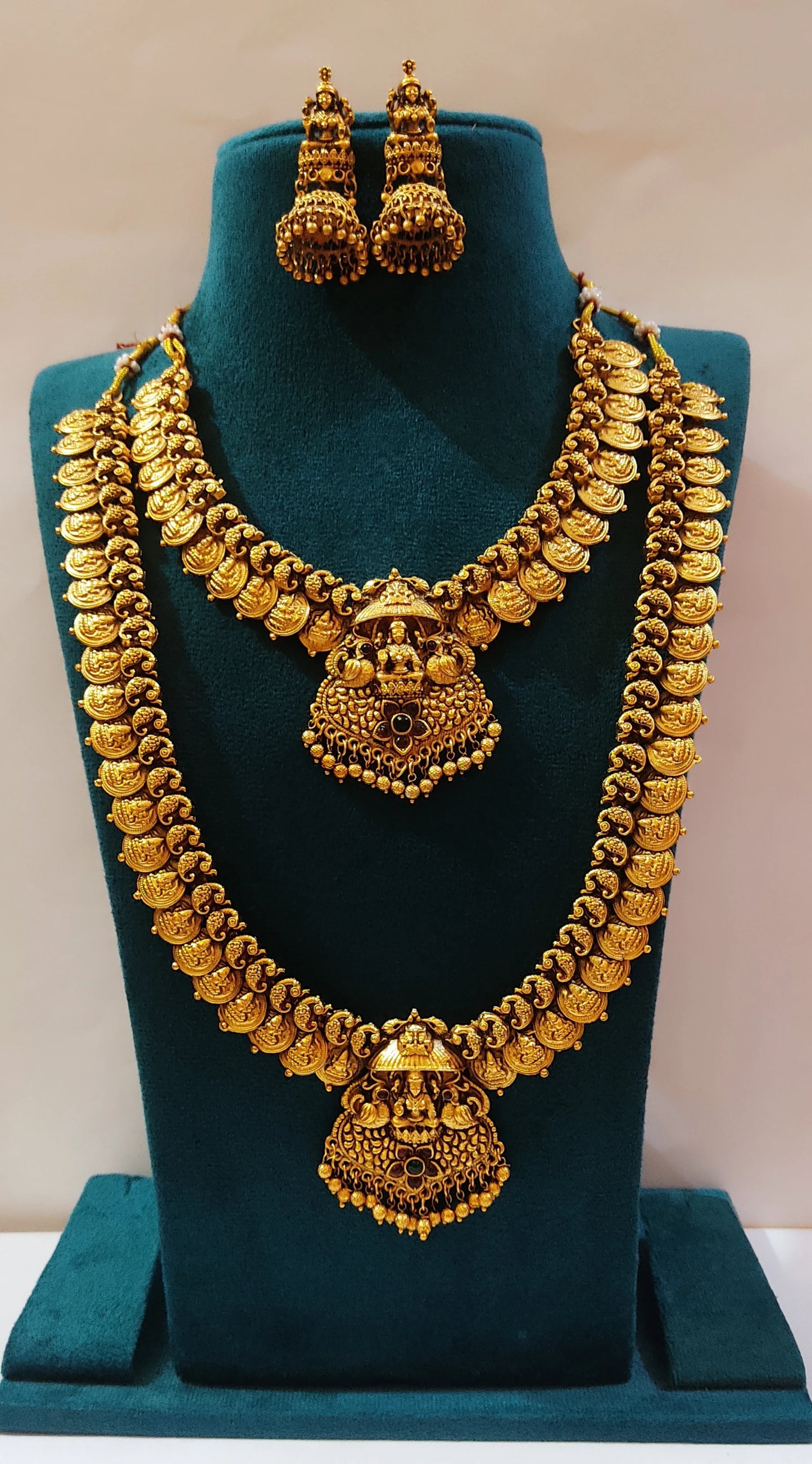a multi-layered Lakshmi motif antique gold finish temple jewelry set on a green mannequin