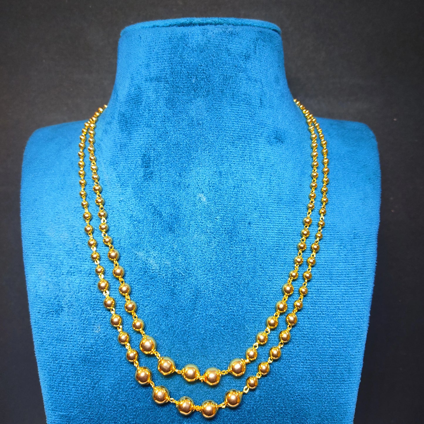 Gold plated necklace on a blue velvet mannequin bust