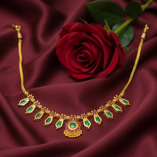 Gold plated Nagapadam necklace with green gemstones and red rose on maroon fabric