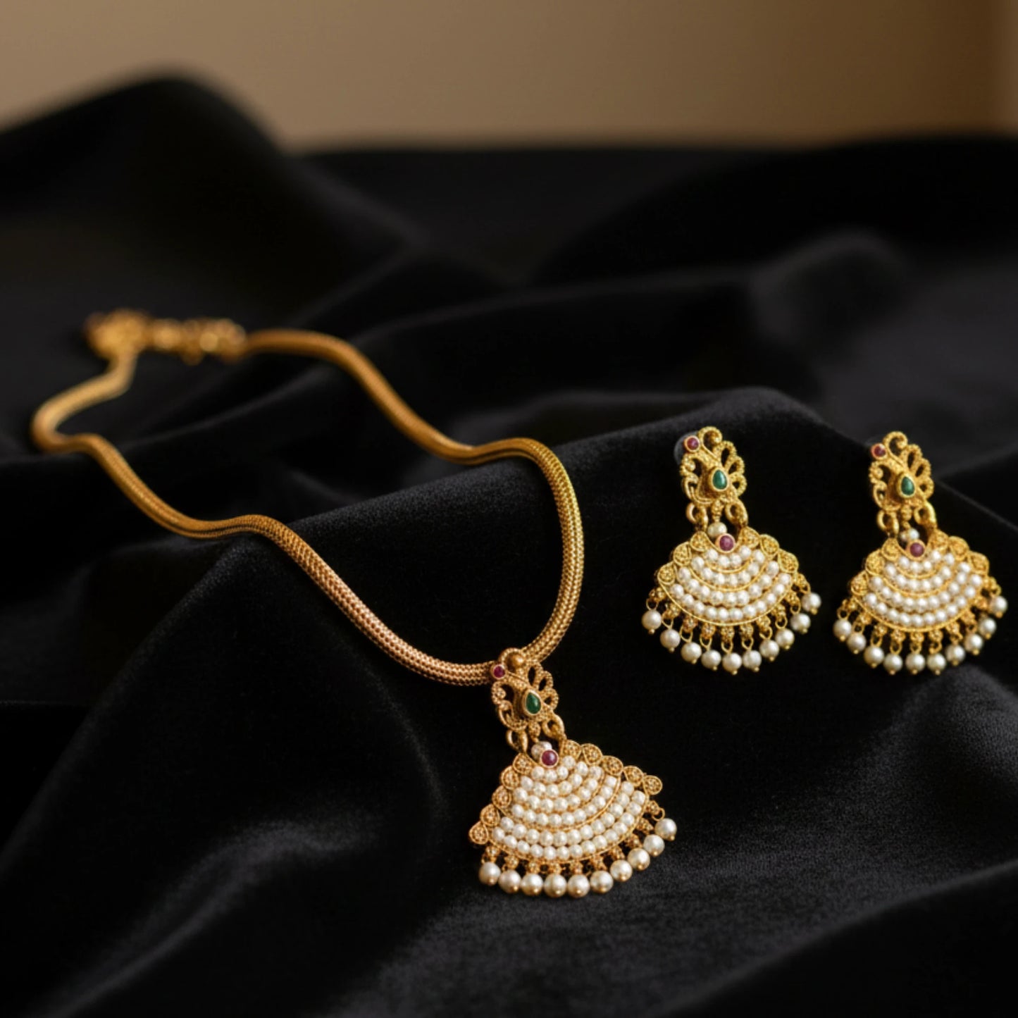 Antique Gold Finish necklace with pearl pendants and matching earrings on a black fabric background