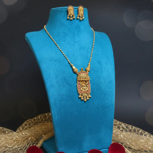 Antique Gold toned necklace and earrings on a blue mannequin with a dark background