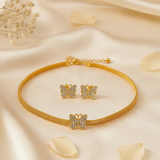 Gold toned butterfly-themed jewelry set on a soft beige fabric background