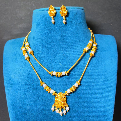 traditional gold-plated double-layer necklace set with a Goddess Laxmi pendant and white pearls displayed on a vibrant blue velvet mannequin bust, including matching Laxmi drop earrings.