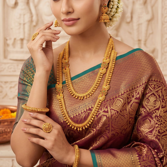 Model wearing Antique gold plated temple jewelry set featuring a long haram necklace, a matching short choker necklace, and bell-shaped jhumka earrings with traditional South Indian spiked golden bead and floral design