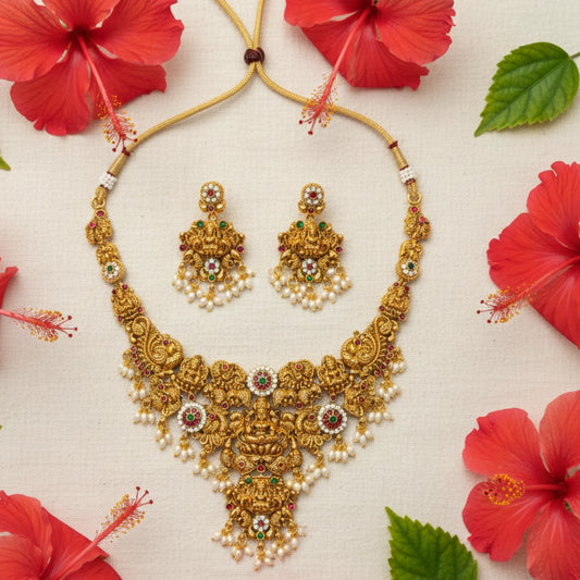 Antique gold plated bridal collection necklace and earrings with red flowers on a beige background