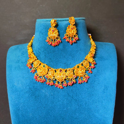 A traditional South Indian Guttapusalu-style short choker necklace and matching drop earrings in a matte antique gold finish displayed on a blue mannequin