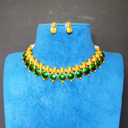 Antique Gold-tone necklace and matching earrings with green teardrop-shaped enamel coated pendants, displayed on a blue velvet jewelry bust against a dark gray background.