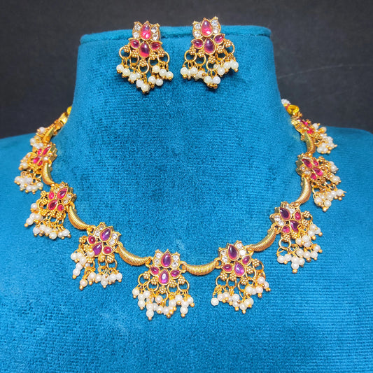 Antique Gold Finish Choker necklace with red kemp stones and pearl droplets on a blue velvet stand