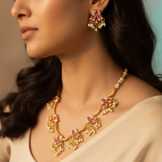 Close-up of a woman wearing a Antique Gold Finish Kemp stones and pearl droplets choker necklace and earrings.