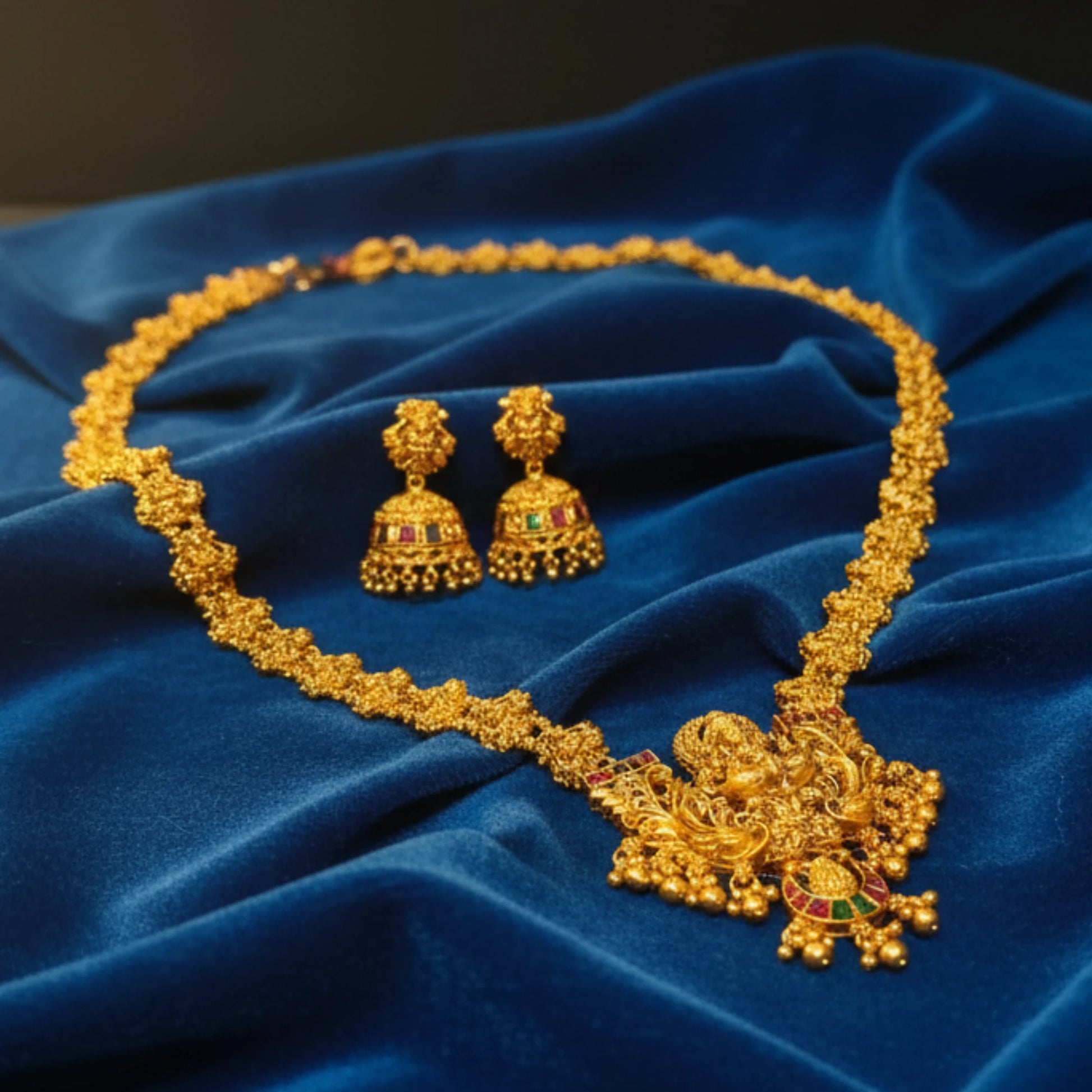 Antique Finish temple Lakshmi haram with matching earrings on a blue velvet cloth