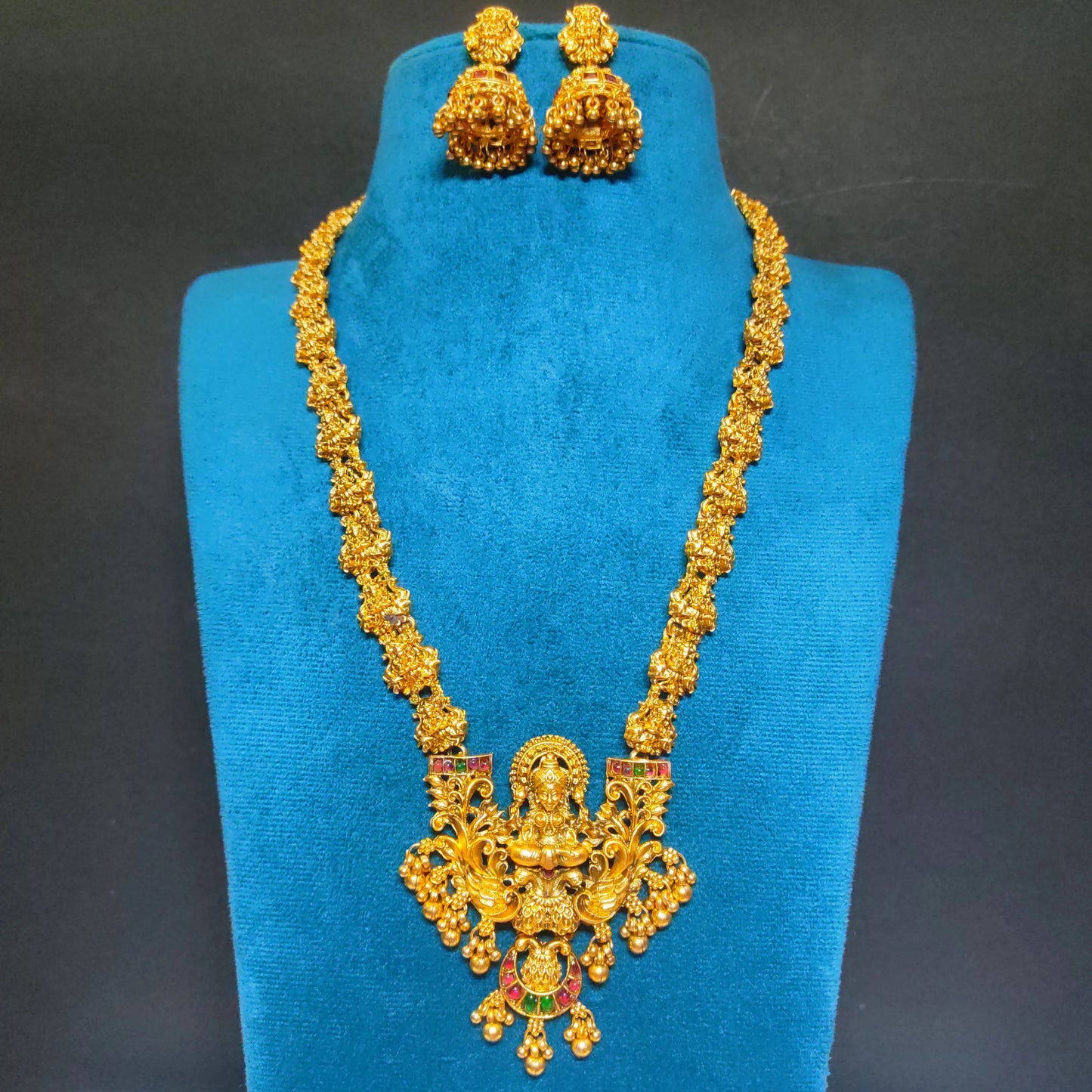 Antique Finish temple Lakshmi haram with matching earrings on a blue mannequin