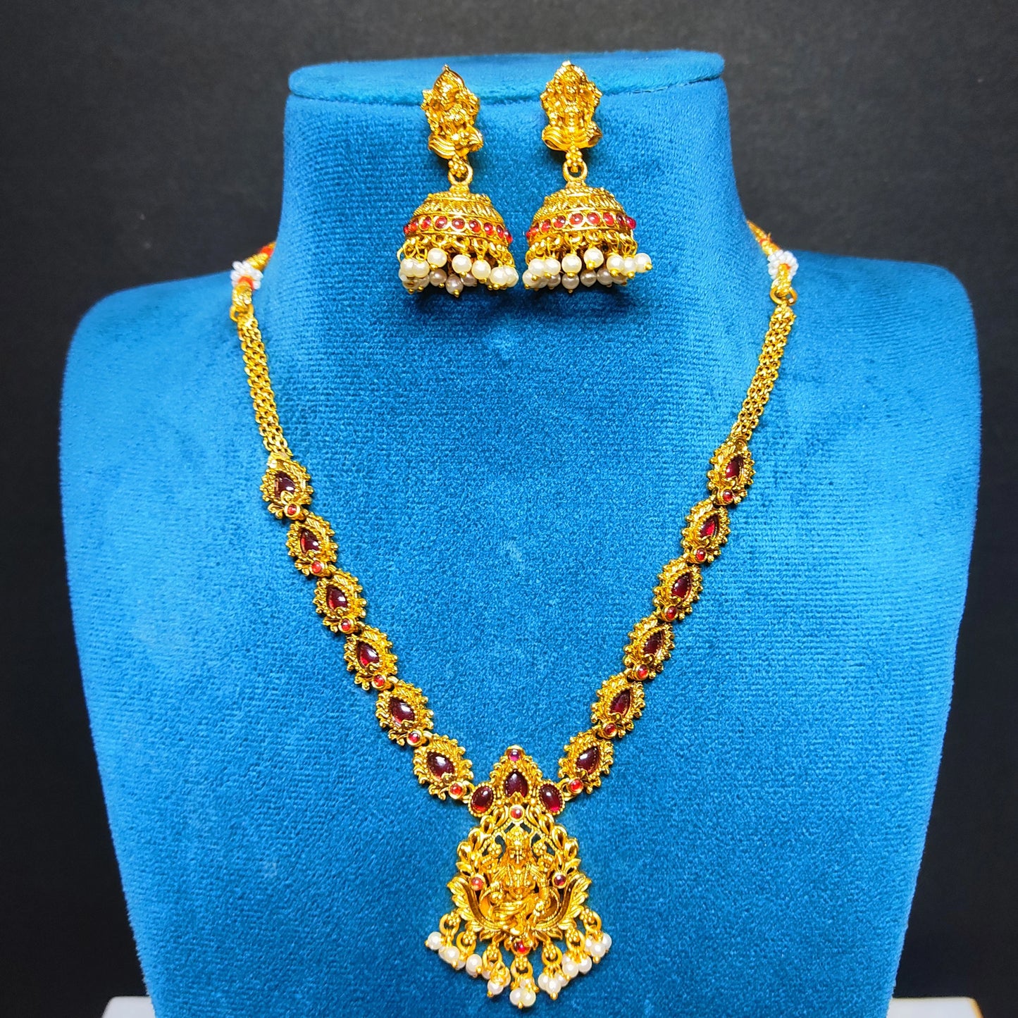 antique gold finish lakshmi pendant necklace with red stones in a mannequin