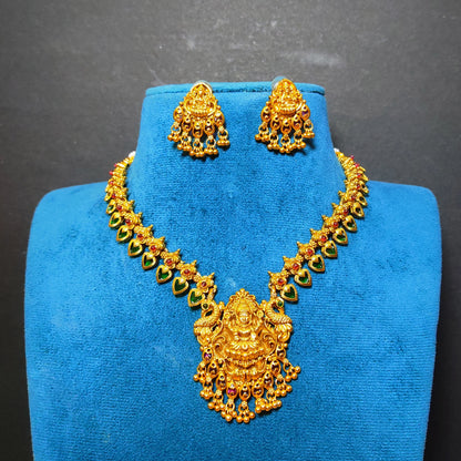 Gold-toned traditional necklace and matching earrings displayed on a blue jewelry bust against a dark gray background.
