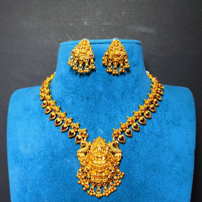 Gold-toned traditional necklace and matching earrings displayed on a blue velvet jewelry bust against a dark gray background.