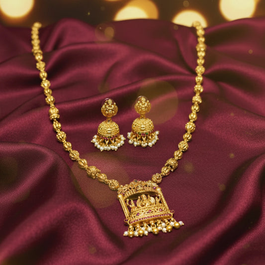 antique gold finish lakshmi pendant haram with matching earrings on a maroon satin cloth