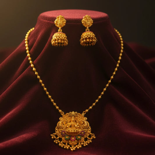Antique Gold finish necklace with pendant and matching earrings on a red velvet stand.