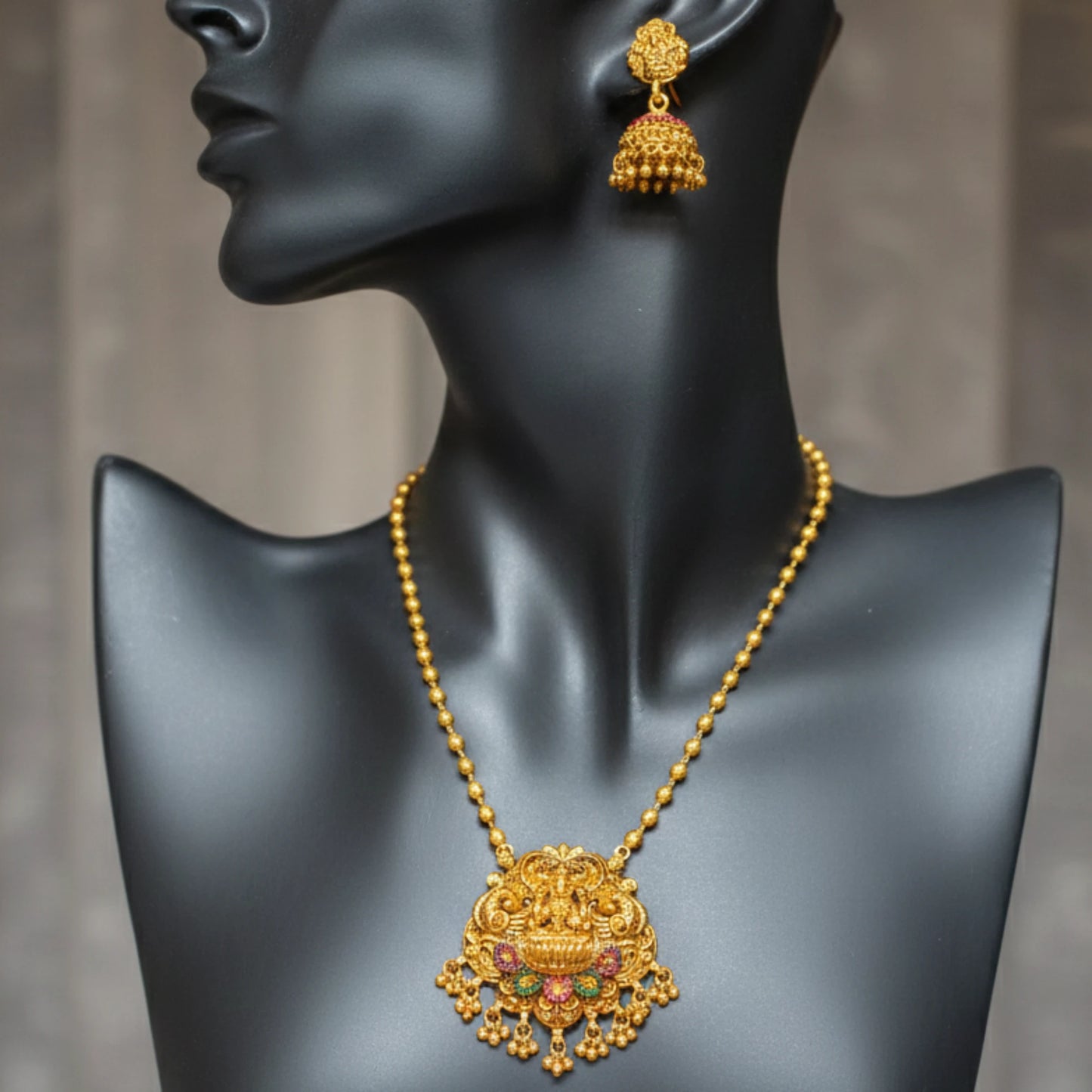 Antique Gold finish necklace and earrings on a black mannequin against a gray background
