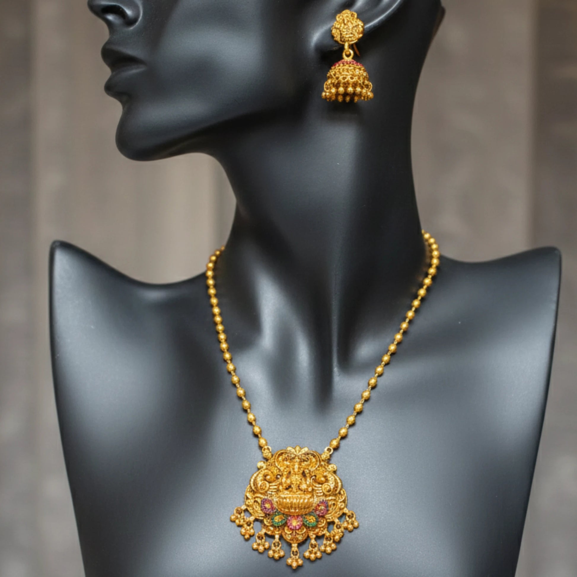 Antique Gold finish necklace and earrings on a black mannequin against a gray background