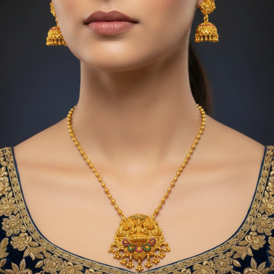 Woman wearing a antique gold finish necklace and earrings on a dark background