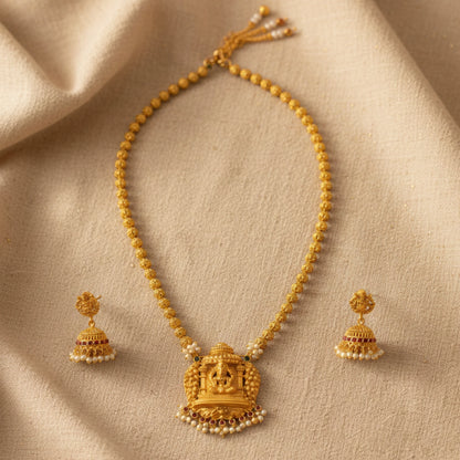Antique Gold finish necklace with matching earrings on a beige fabric background