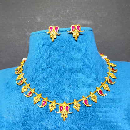 Gold-toned traditional jewelry set featuring a necklace and matching earrings with pink/lavender enamel accents, displayed on a blue velvet jewelry bust against a dark gray background.