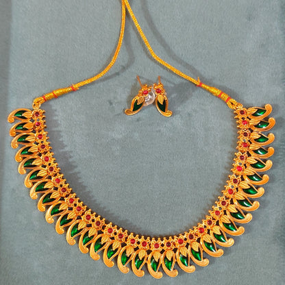 Antique Gold Finish Mango necklace with green and red stones on a gray background