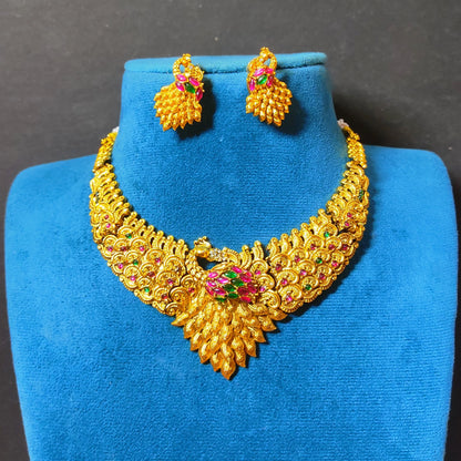 Traditional Indian matte antique gold peacock choker necklace and matching statement stud earrings beautifully arranged on a soft, blue mannequin