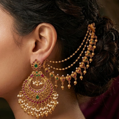A pair of traditional Indian 3-layer antique gold mattal ear chains with ruby red and emerald green kemp stones, displayed beautifully