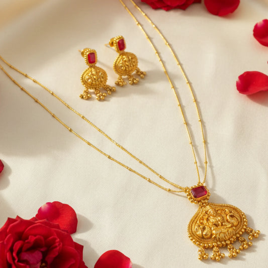 Antique Gold Finish necklace and earrings with red stones on a beige surface with red flowers.