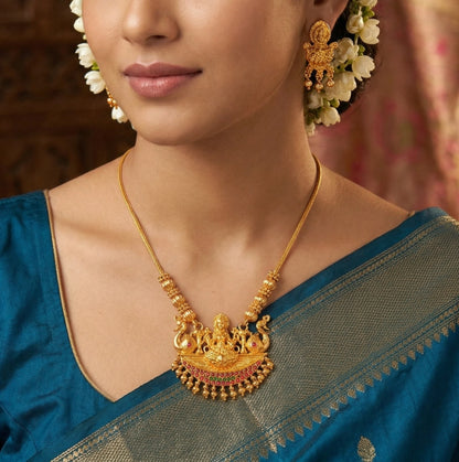 Woman wearing a antique gold finish necklace and earrings with a blue saree