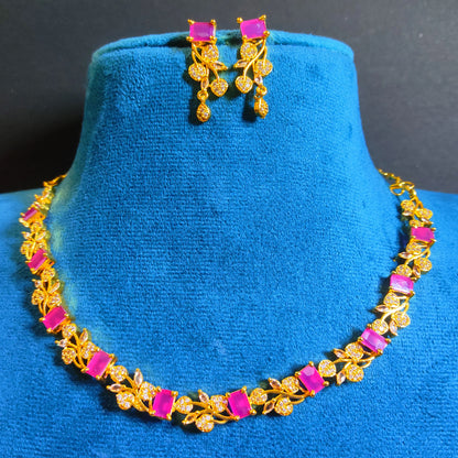 Gold Plated Necklace and earrings with pink stones on a blue stand against a dark background