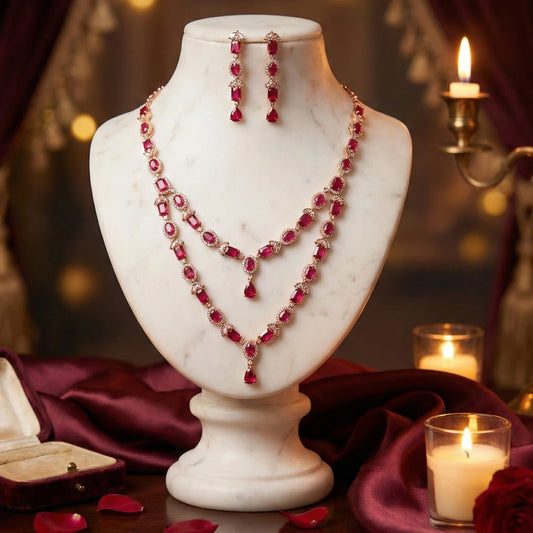Red AD stone Rose Gold necklace and earrings on a marble bust with candles and satin fabric in the background