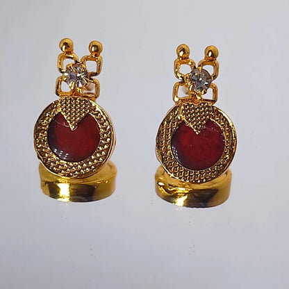 Pair of gold plated earrings with red palakka and clear stones on a white background