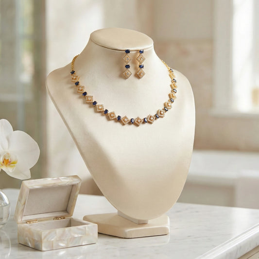 Gold plated necklace and earring set with sapphire blue stones and white diamonds in a geometric rhombus pattern.