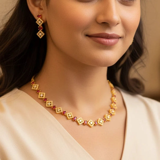Gold plated necklace and earring set with red stones and white diamonds in a geometric rhombus pattern.