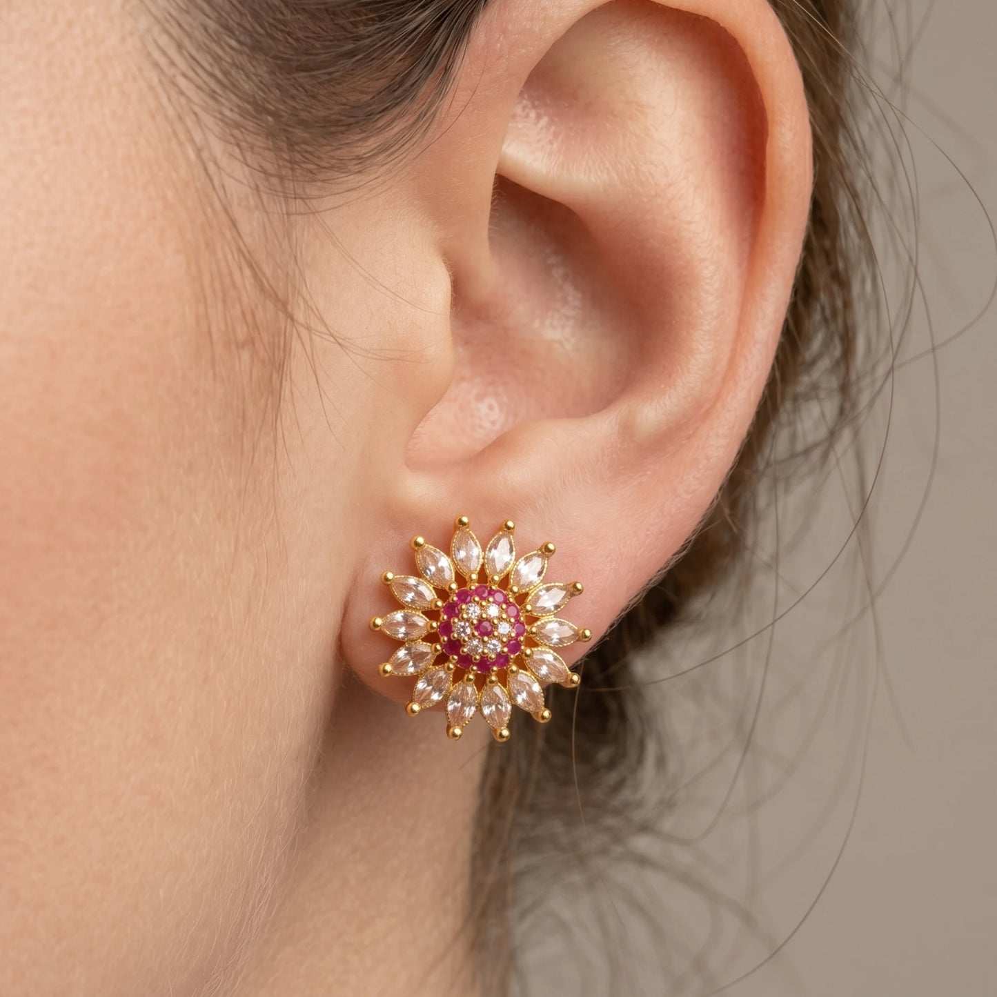Ear wearing a gold plated floral ad stud earrings in multicolor that is pink and white ad stones with gold accents