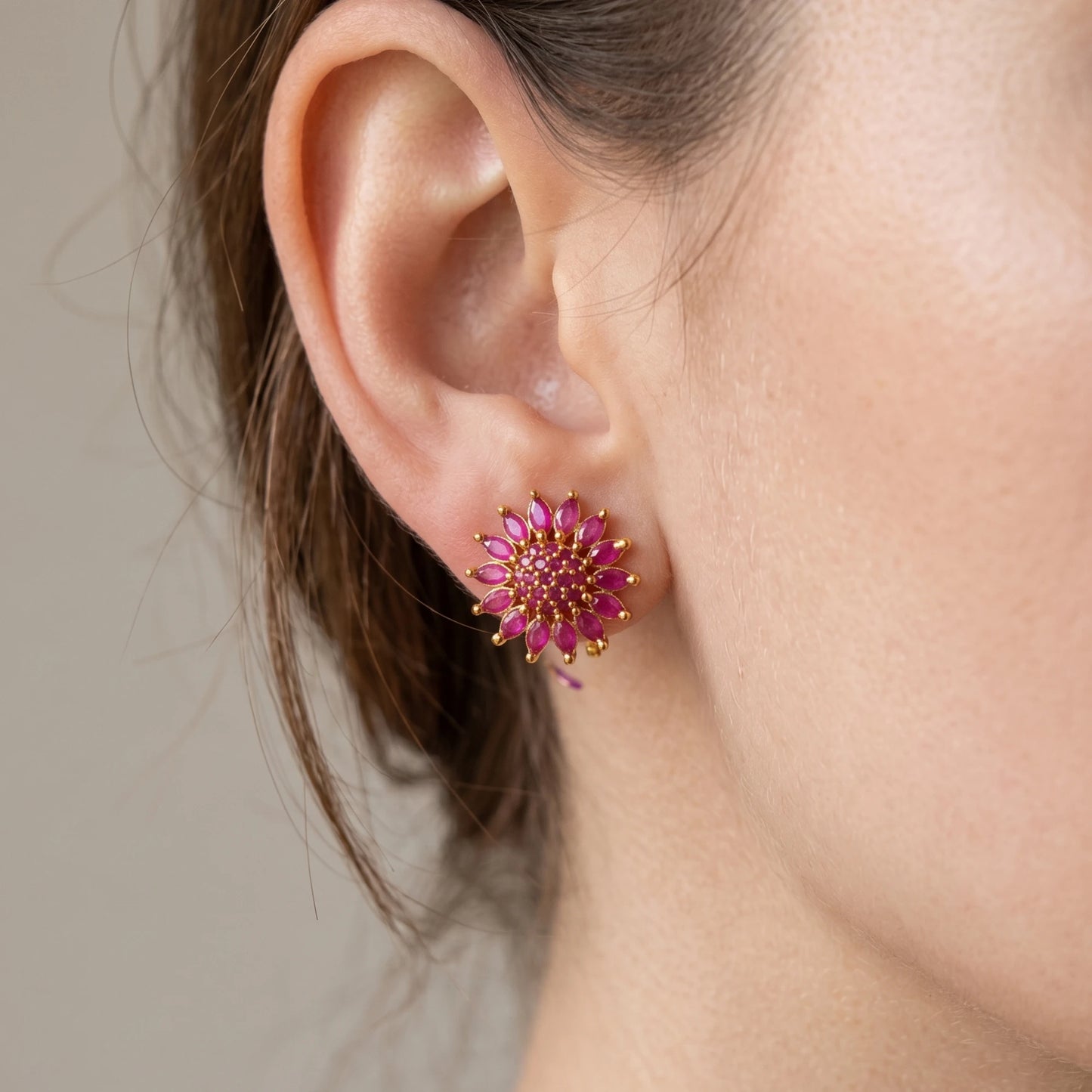 Close-up of an ear wearing a Gold plated pink floral AD Stud earring with gold accents.