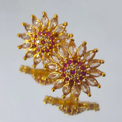 Gold plated AD floral stud earrings in multicolor displayed in a pattern on a reflective surface