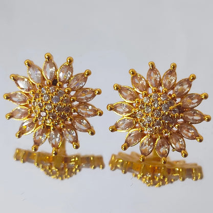 Gold plated AD floral sun burst stud earrings with clear stones on a white background