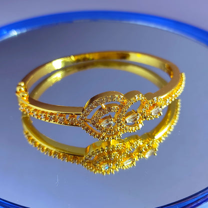 Gold plated bracelet with intricate design on a reflective blue surface