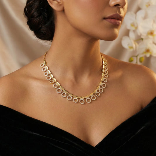 Woman wearing a gold-plated necklace with a blurred floral background