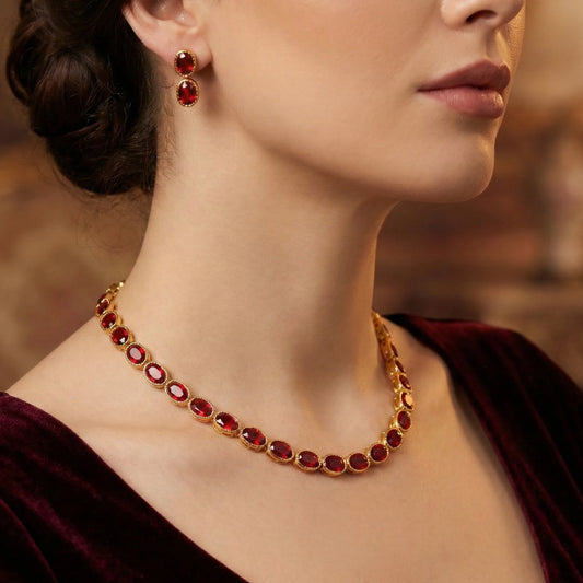 Close-up of a woman wearing a gold plated necklace with red gemstones and matching earrings.