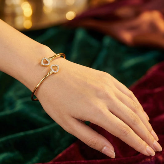 Gold plated bracelet with heart-shaped charms on a hand against a blurred background