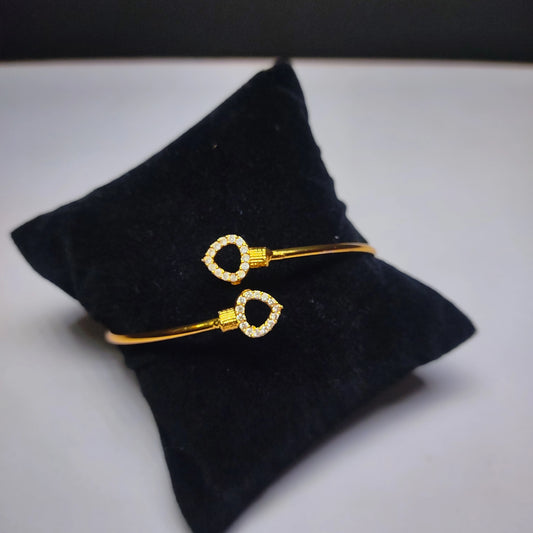 Gold plated bracelet on a black velvet cushion with a white background