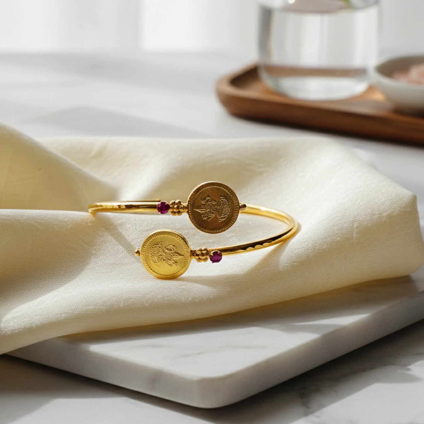 Gold plated bracelet with circular charms on a white napkin