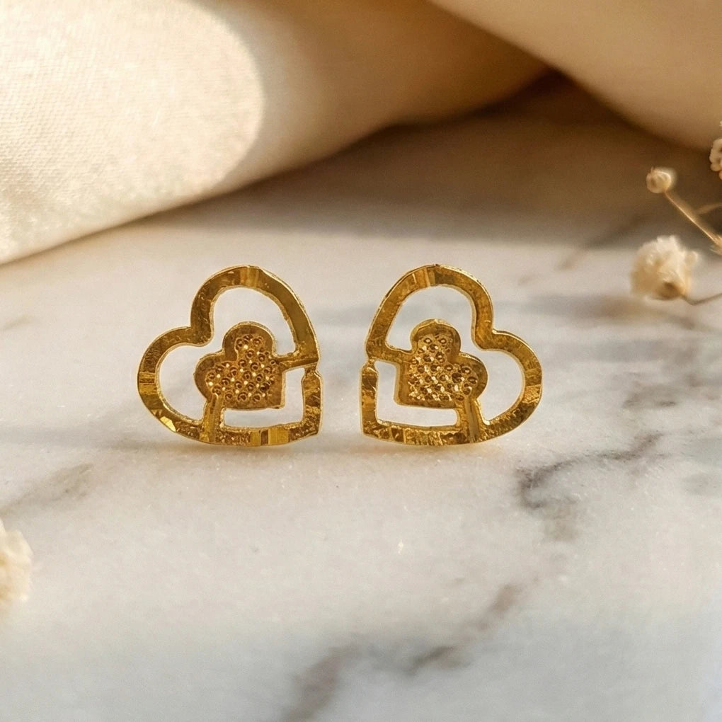 Gold plated heart-shaped earrings on a marble surface
