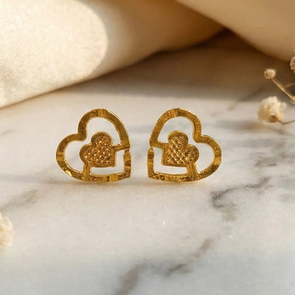 Gold plated heart-shaped earrings on a marble surface