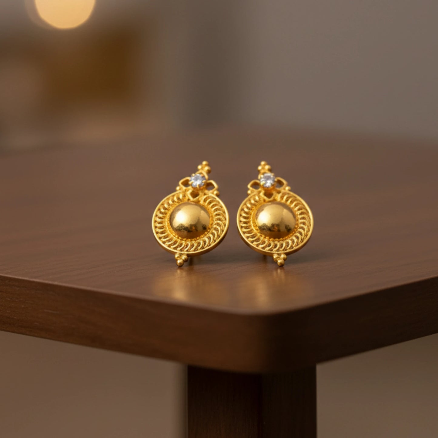 Pair of gold plated Dome stud earrings on a wooden surface with a blurred background