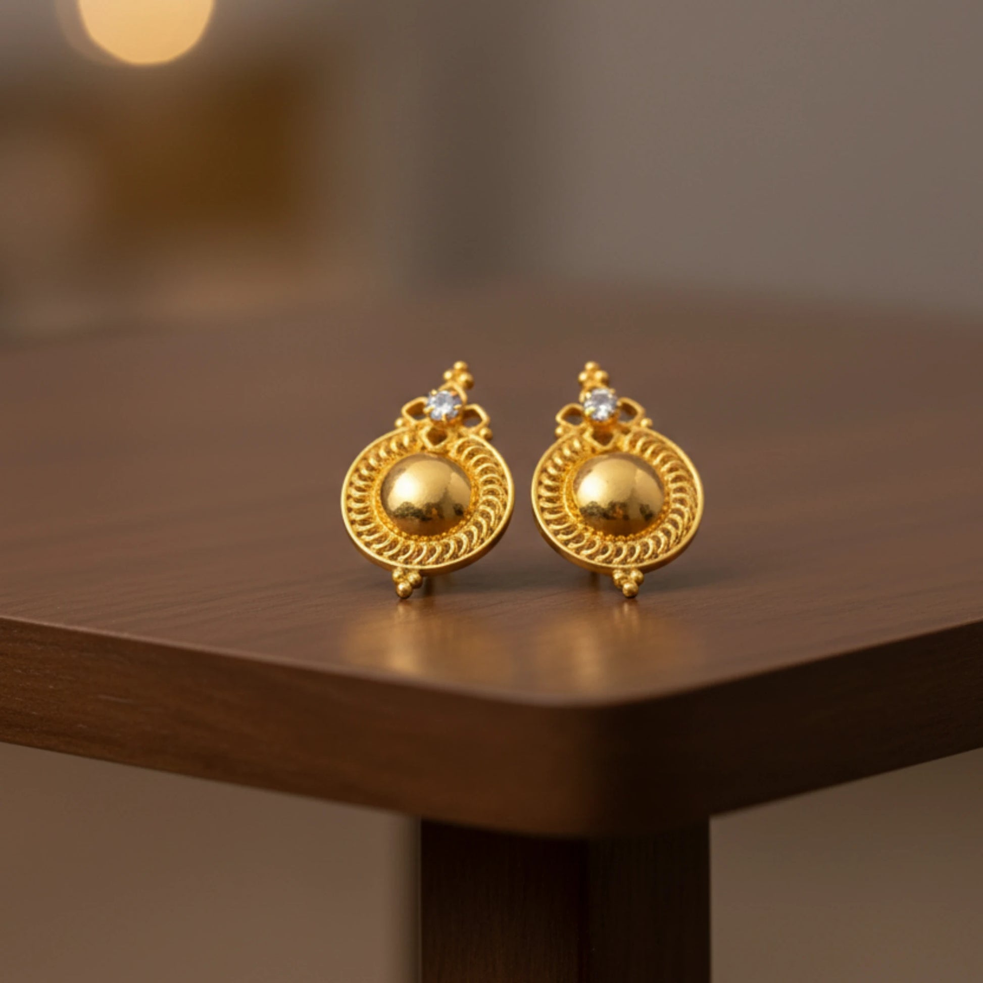 Pair of gold plated Dome stud earrings on a wooden surface with a blurred background